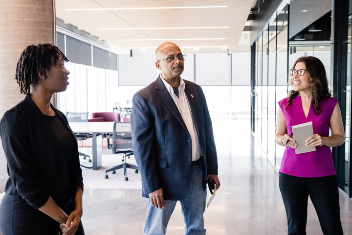 three coworkers in hallway having a group discussion
