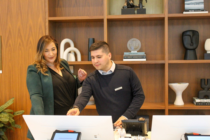 two hotel employees looking at computer at front desk